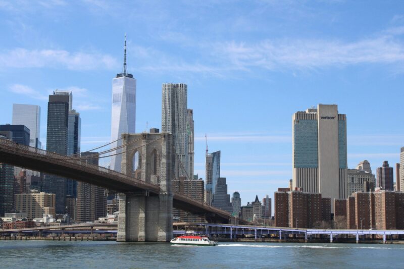 Battello in navigazione davanti al Ponte di Brooklyn e al One World Trade Center