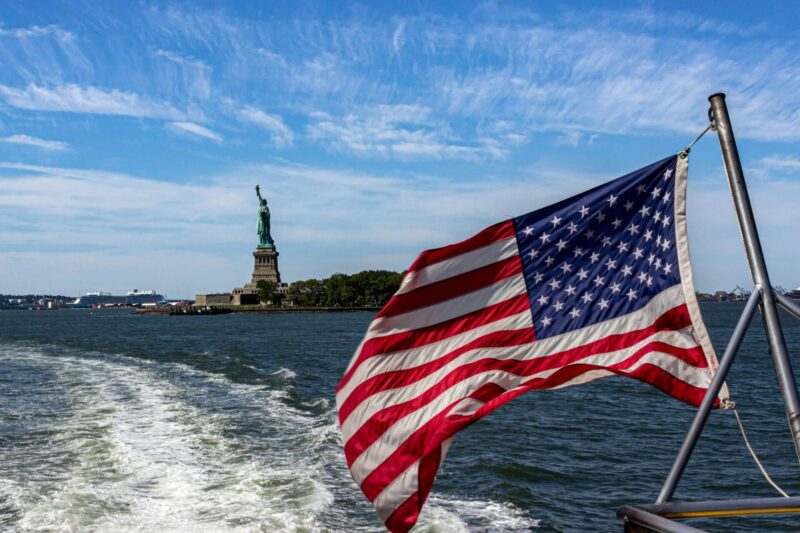 Bandiera americana a poppa del battello con la Statua della Libertà sullo sfondo